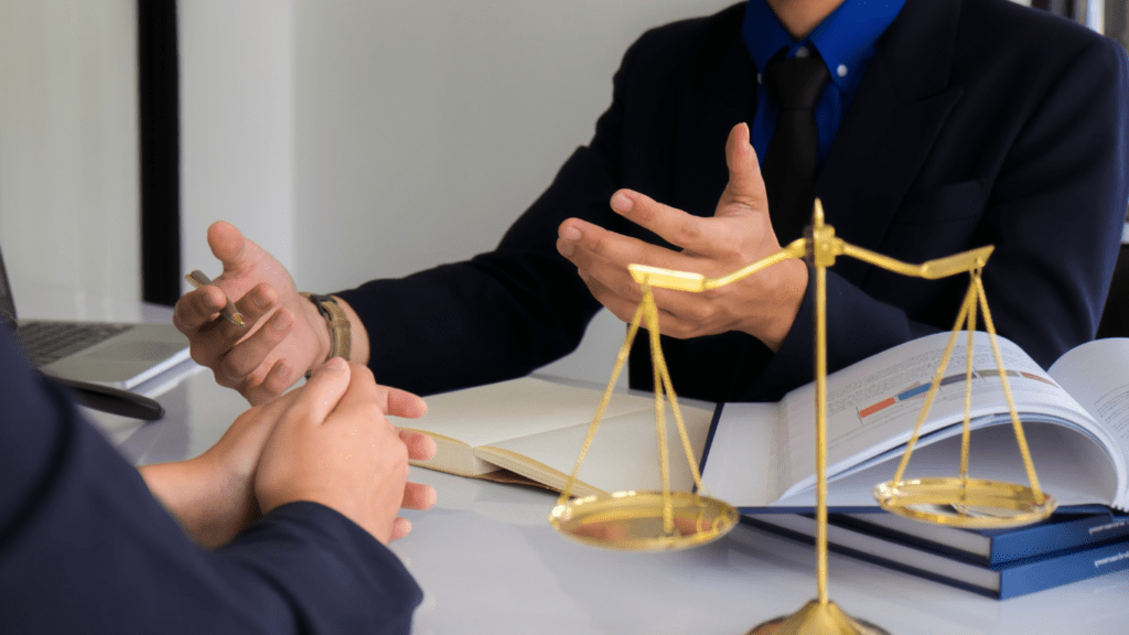 A person in a suit is talking to another person at a desk.