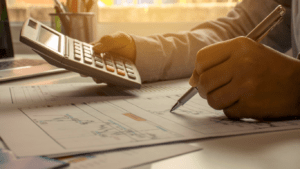 A person in a business suit is using a calculator.