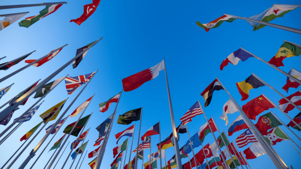 a row of flags on poles in front of a blue sky