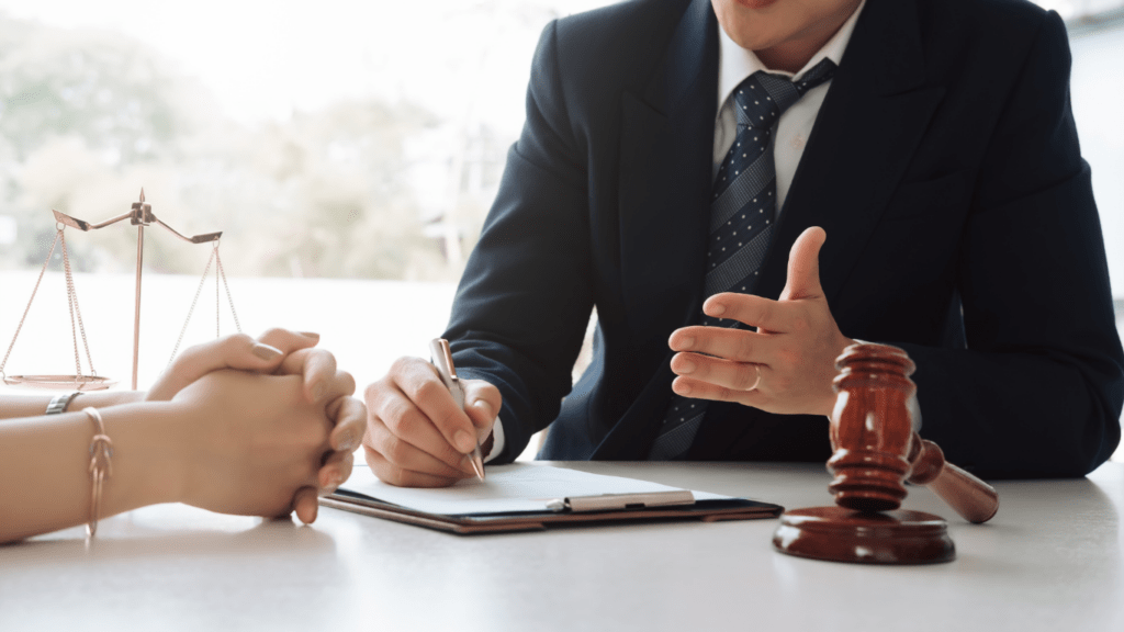 A person in a suit is talking to another person at a desk.