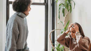 Two people are talking in a living room.