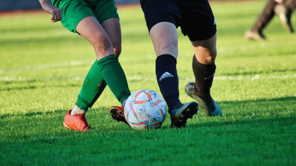 Two individuals are playing soccer on a field.