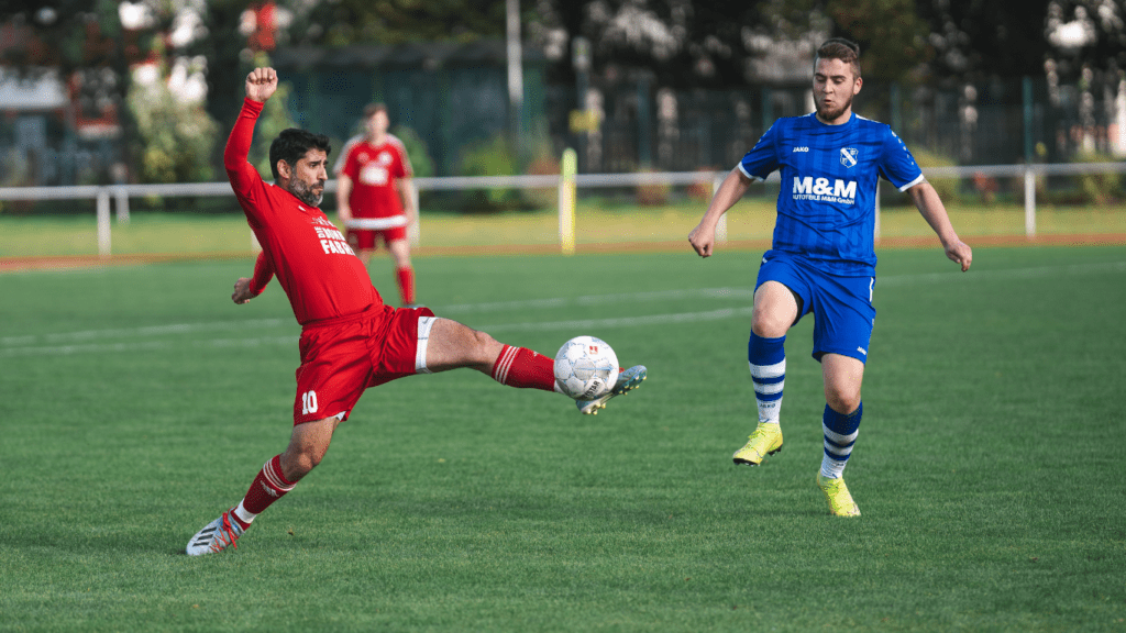 Two individuals are playing soccer on a field.