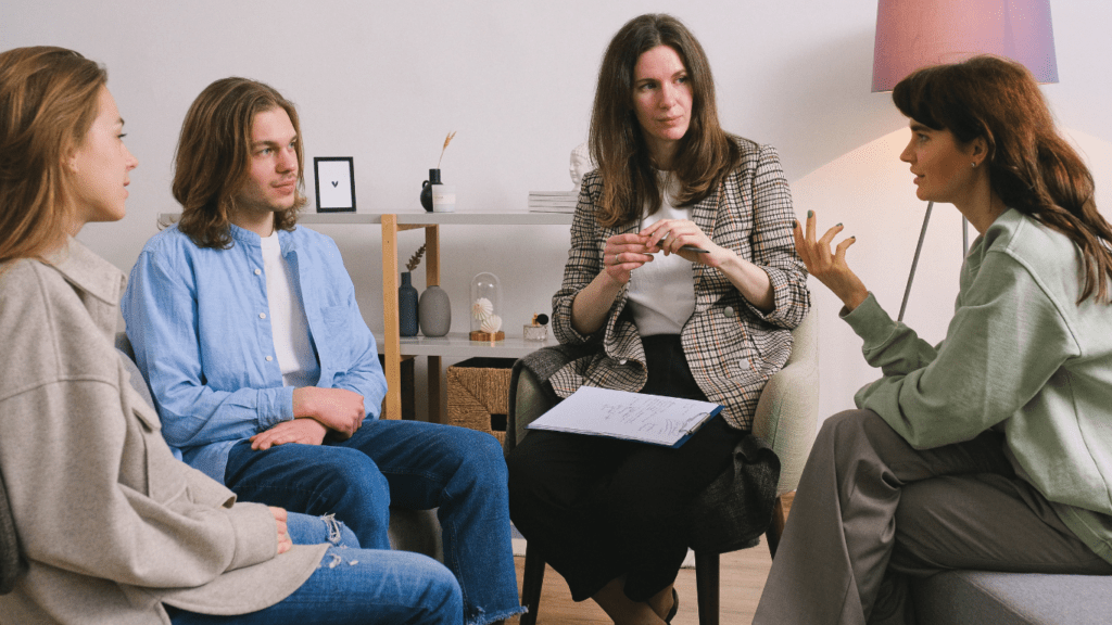 a group of people sitting on a couch talking to each other