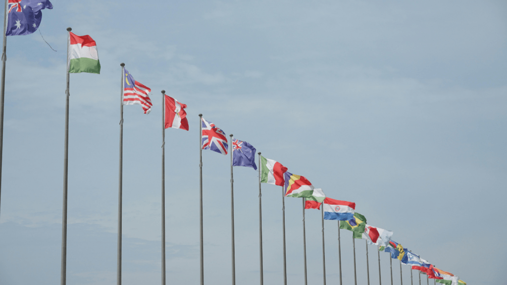 a row of flags on poles in front of a blue sky