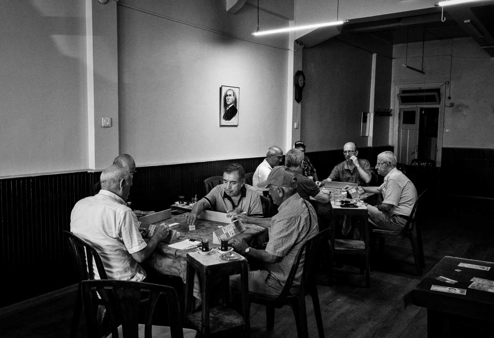 Senior men gathered in a Turkish café playing cards, capturing a slice of leisure in Istanbul.