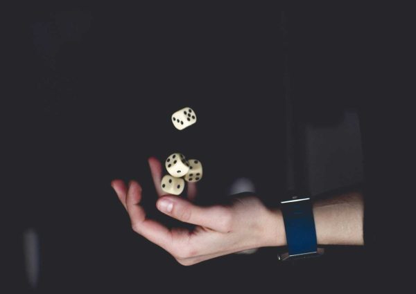 pexels-photo-1111597-1111597 A close-up of a hand tossing several dice against a dark background, symbolizing chance and luck.