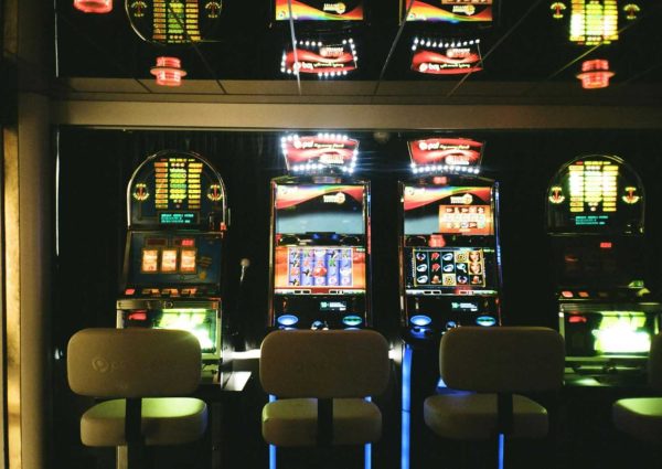 pexels-photo-3021120-3021120 Slot machines in a dimly lit casino with reflective ceiling and empty chairs.